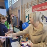 Kobieta wręczająca ulotki przy stoisku Targów pracy